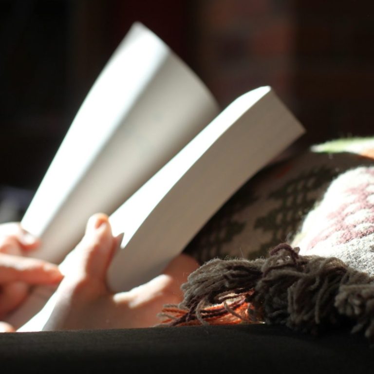 Clases flexibles Personas leyendo un libro en un entorno acogedor y con una manta encima.
